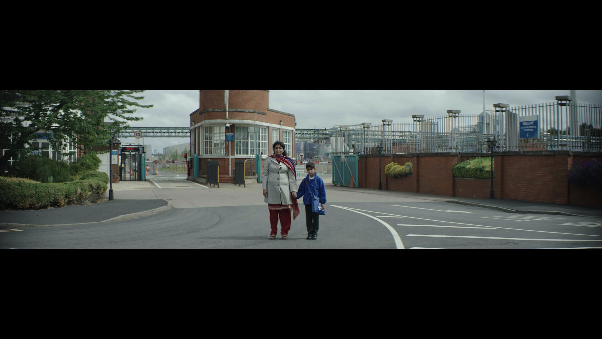 Indi, 2022, film still: a mother and child crossing a Black Country street, lit by a single street lamp.