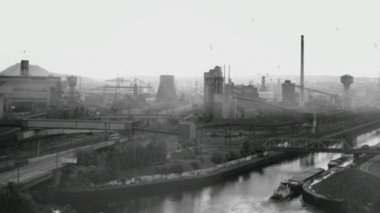 Year Zero: Black Country, archival still: a black-and-white Black Country industrial scene, foundry chimneys above the canal, a barge on the water.